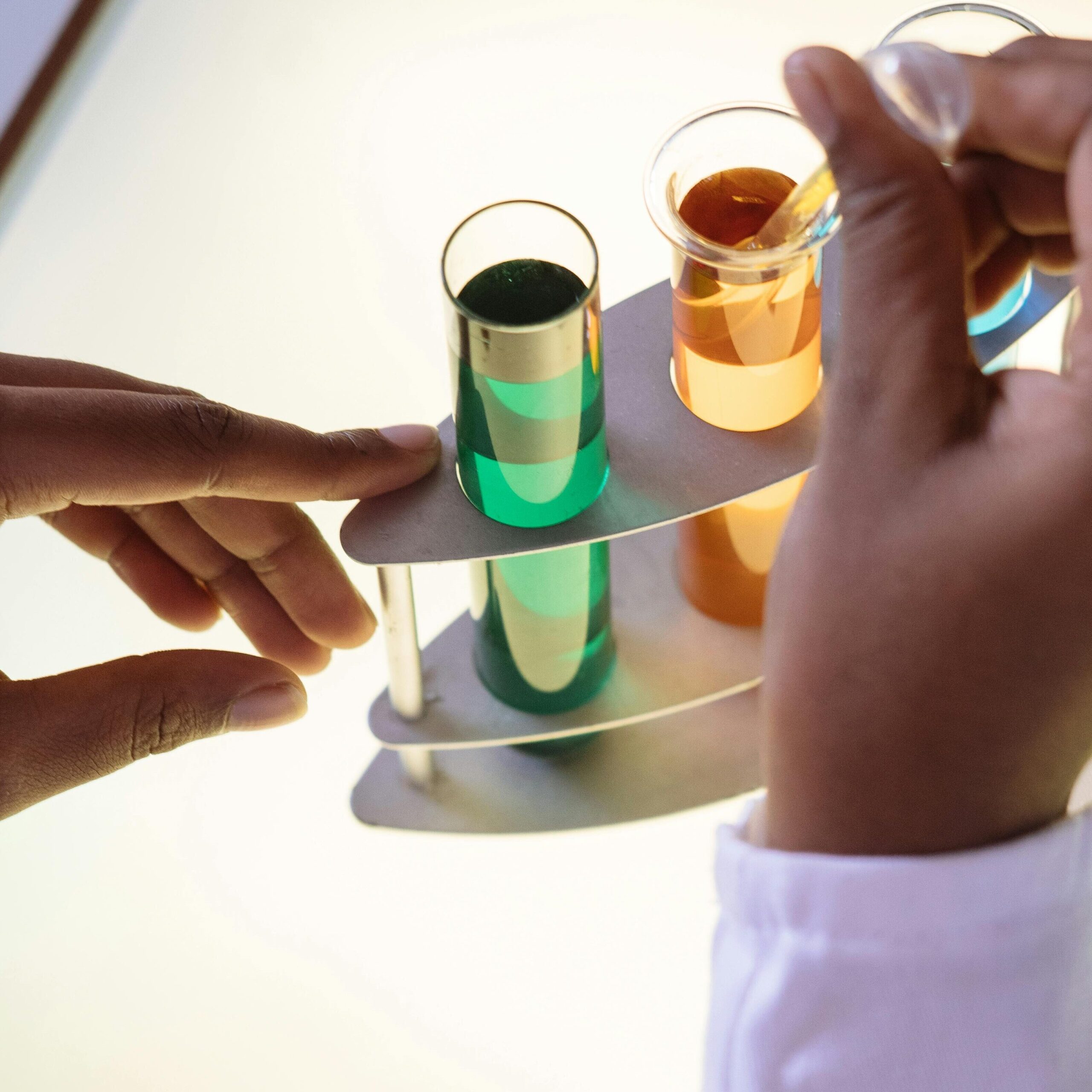 Crop laboratory technician in white uniform using pipette for taking sample from test tube during biochemical experiment in researching center